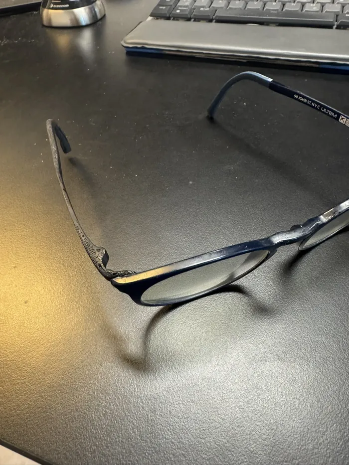 Die Brille mit dem neuen Bügel liegt auf einem Schreibtisch