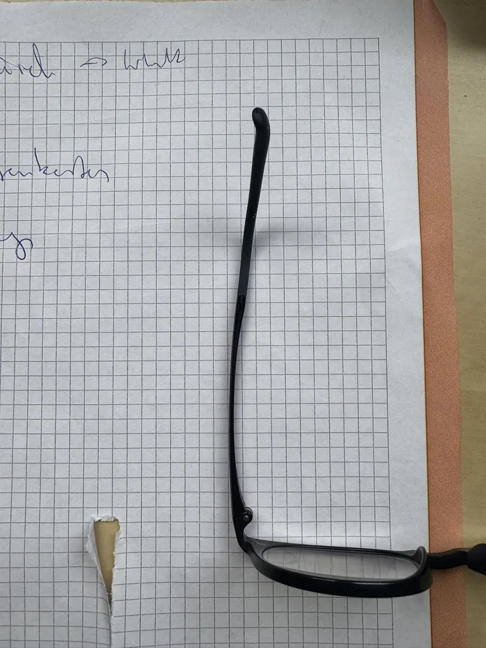 Der gedruckte Bügel sitzt am Brillengestell, das Gestell liegt auf Karopapier