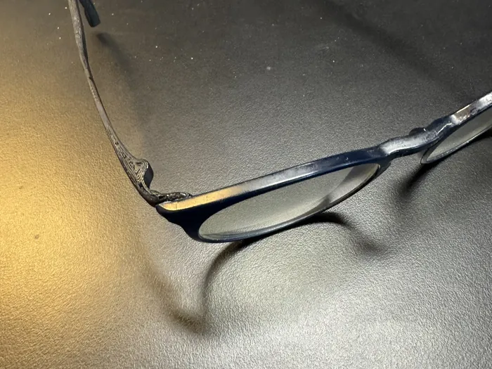 Die Brille mit dem neuen Bügel liegt auf einem Schreibtisch