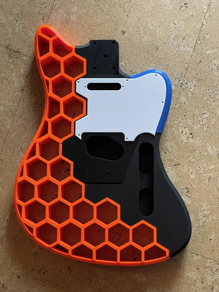 Gitarrenkorpus mit orangefarbener Wabenstruktur, schwarzer Mitte und weißem Schlagbrett