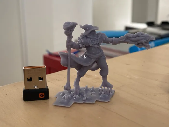 Kleine graue Figur eines Zauberers neben einem USB-Stecker als Größenvergleich