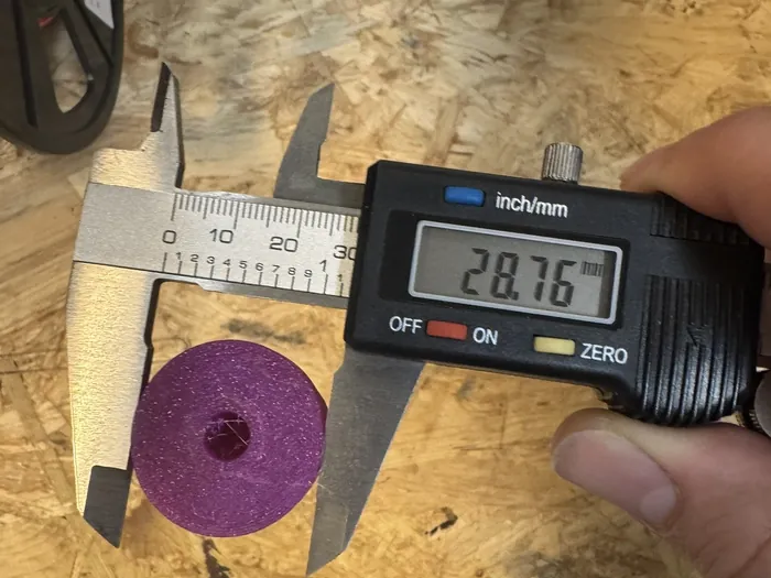 Ein Messschieber misst eine violette, gedruckte Scheibe, die Anzeige zeigt 28,76 Millimeter