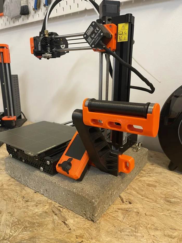 Kleiner 3D-Drucker in Schwarz und Orange auf einer Betonplatte